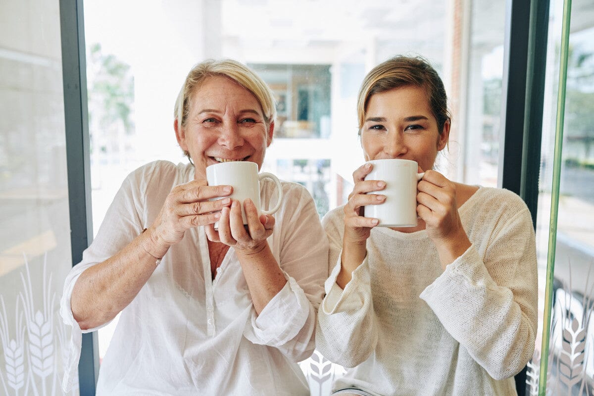 an older woman and a younger woman enjoying coffee together