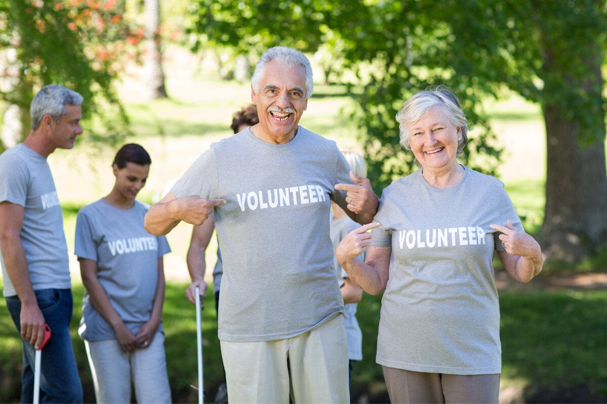 two happy volunteer seniors smiling at the camera