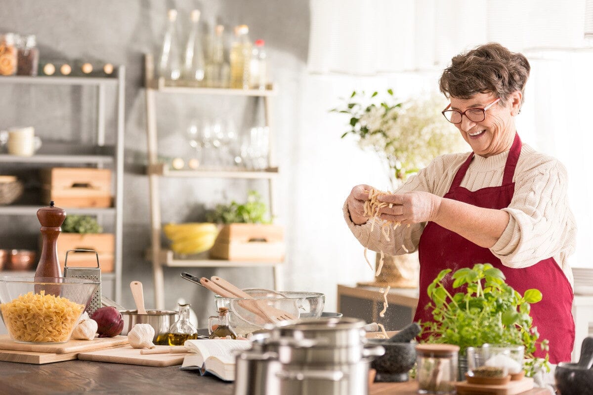 Senior woman happily making noodles from scratch.