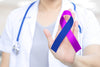 doctor in white lab coat holding up a purple and blue ribbon.