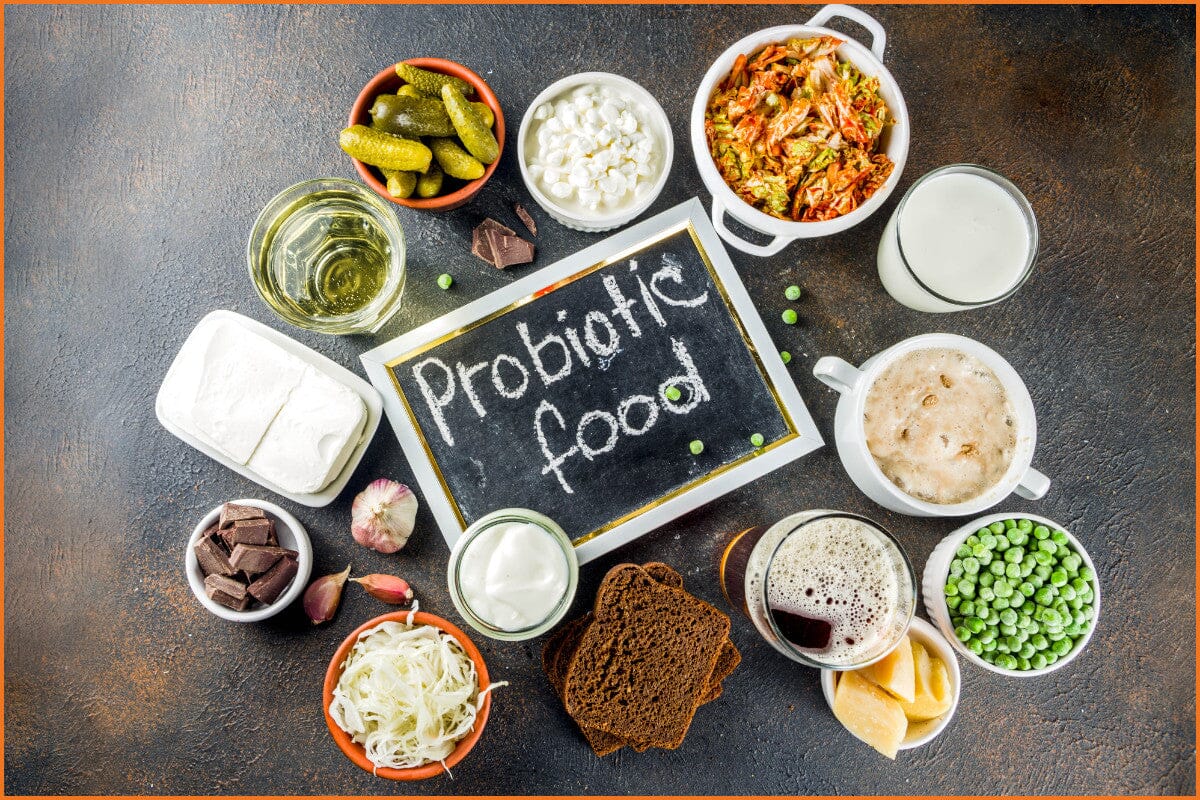 a dark brown and black table with various probiotic foods in bowls surrounding a small blackboard with the words