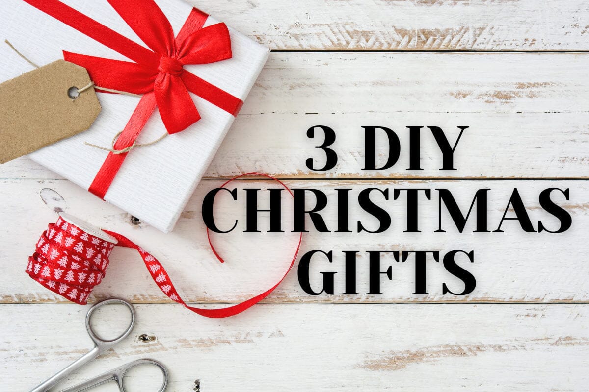 white and red box, red ribbon, pair of scissors sitting on white wood table with the words 
