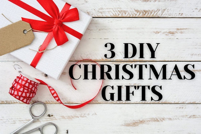 white and red box, red ribbon, pair of scissors sitting on white wood table with the words 
