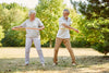 older couple exercising with hula-hoops outside on the grass