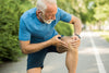 older man who stopped running on a trail outside due to pain in his knee
