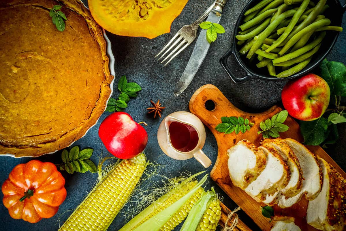 various holiday foods, from pumpkin pie to turkey all spread across a gray table