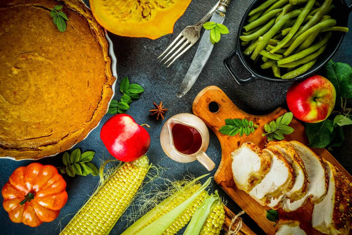 various holiday foods, from pumpkin pie to turkey all spread across a gray table