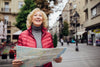 retired woman traveling alone, map in hands, smiling and looking around