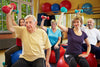 group of seniors sitting on chairs while working out with dumbbells
