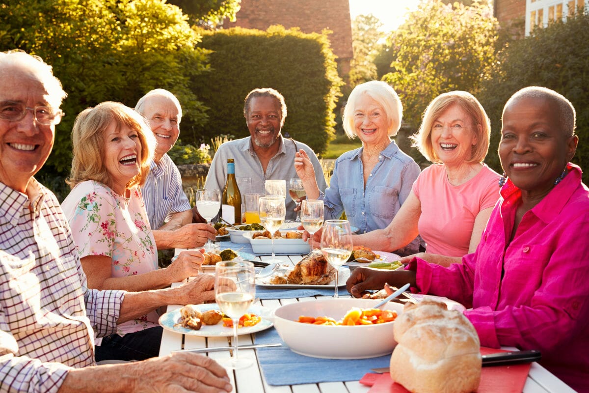 group of seniors sitting at a table outside enjoying food together