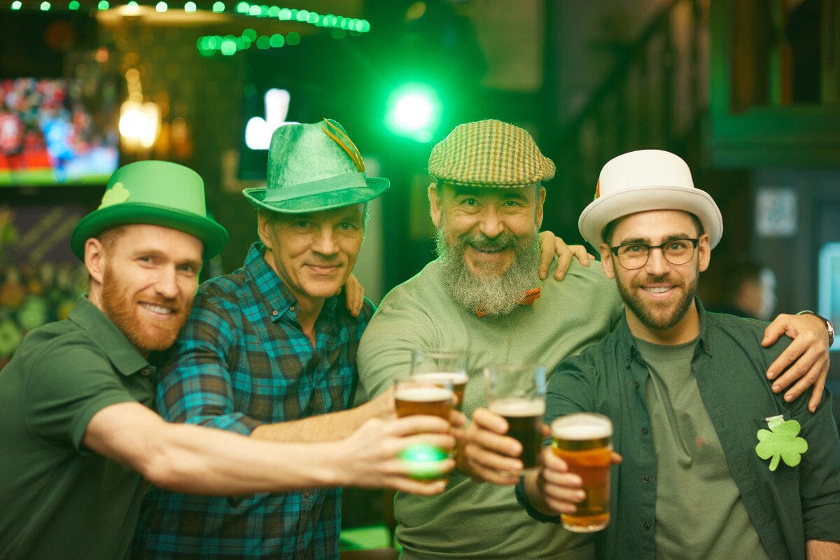 group of different aged men, wearing St. Patrick's Day attire and cheering with beer