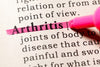close-up view of the word Arthritis defined in the dictionary and highlighted in pink.