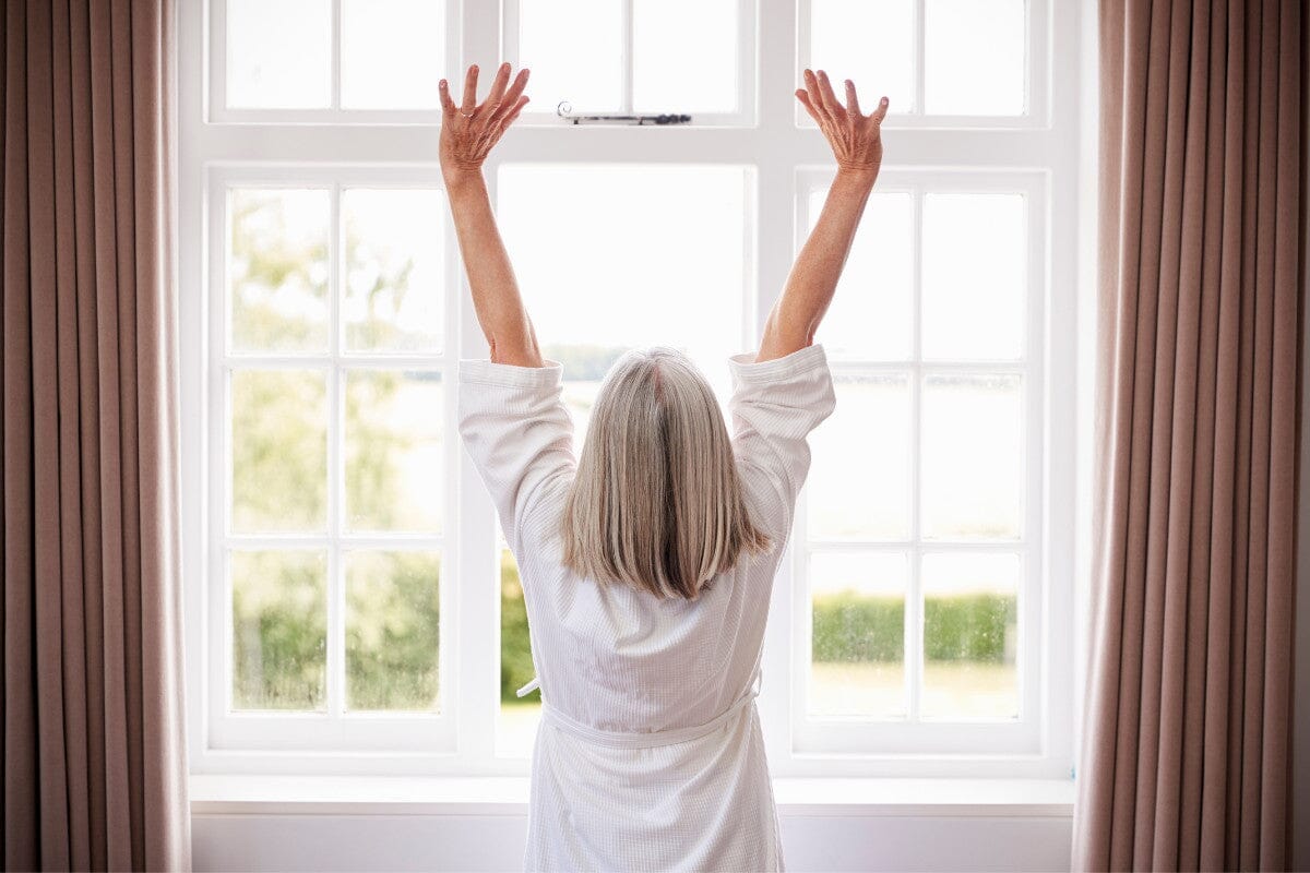 Senior woman stretching in the window.