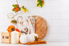 white kitchen wall tile with various pumpkins and gourds, fall leaves, and two wooden cutting boards