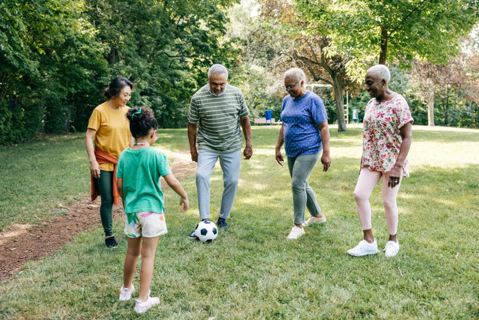 group of seniors playing soccer with a young kid