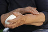 older woman moisturizing the dry skin on her arms.