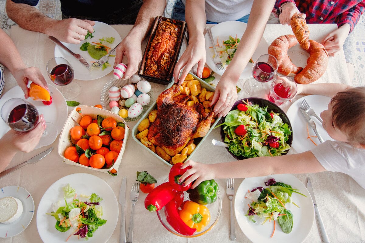 looking down on a table filled with delicious foods and Easter eggs. family hands grabbing at different plates of food.