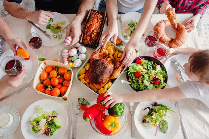 looking down on a table filled with delicious foods and Easter eggs. family hands grabbing at different plates of food.