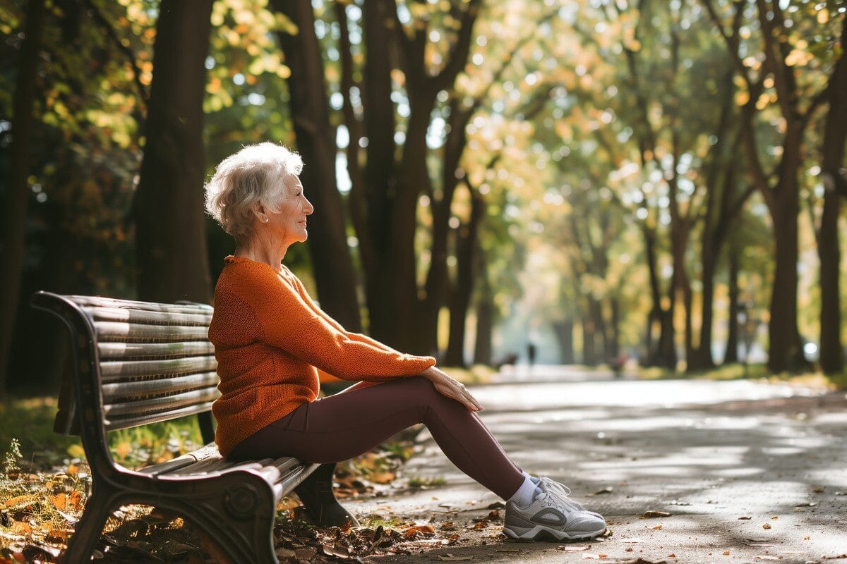 Senior woman stretching her legs on a park bench in fall.