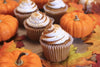 pumpkin spice cupcakes and small orange pumpkins.