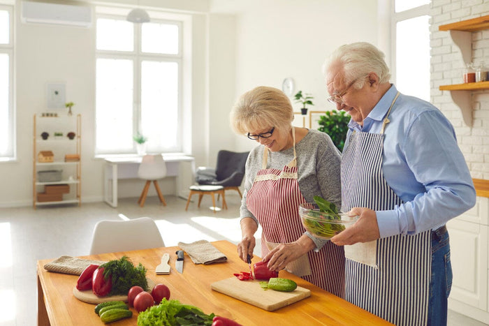 two seniors cooking a healthy salad in their kitchen at home.