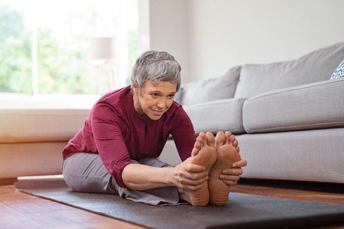 senior woman stretching her hamstrings on a yoga mat.