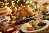 holiday feast on table with turkey in the center and Christmas tree in the background.