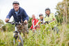 group of middle-aged people and seniors riding bikes through a field