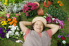 mature woman smiling and laying in the grass as she takes a break from working on her garden