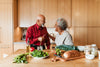 senior couple smiling and preparing a meal together