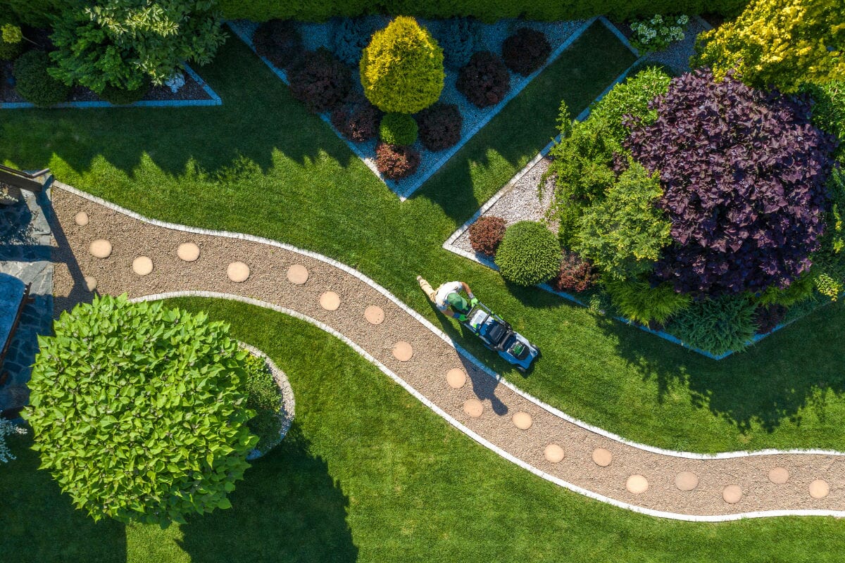 Aerial view of someone mowing a beautifully landscaped garden lawn.
