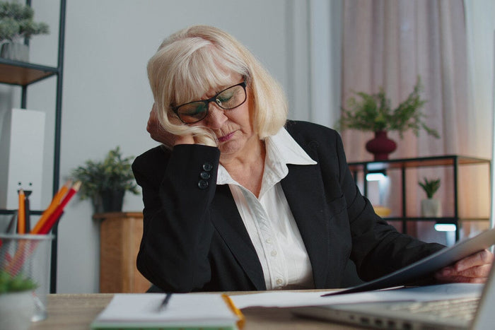 Tired sleepy senior business woman falling asleep sit at home office desk with computer