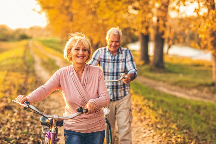 senior couple biking on a trail during autumn.