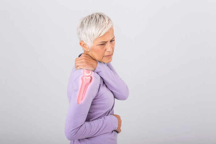 older woman holding her shoulder in pain.