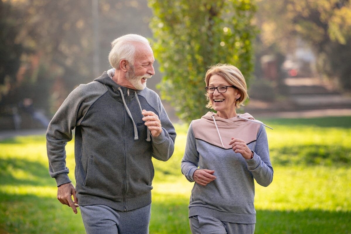 senior couple fast-walking outside in the park.