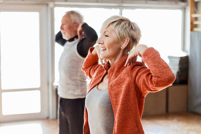 Senior couple stretching together indoors.