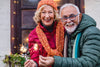 senior couple standing outside wearing winter coats, smiling as they hold sparklers.