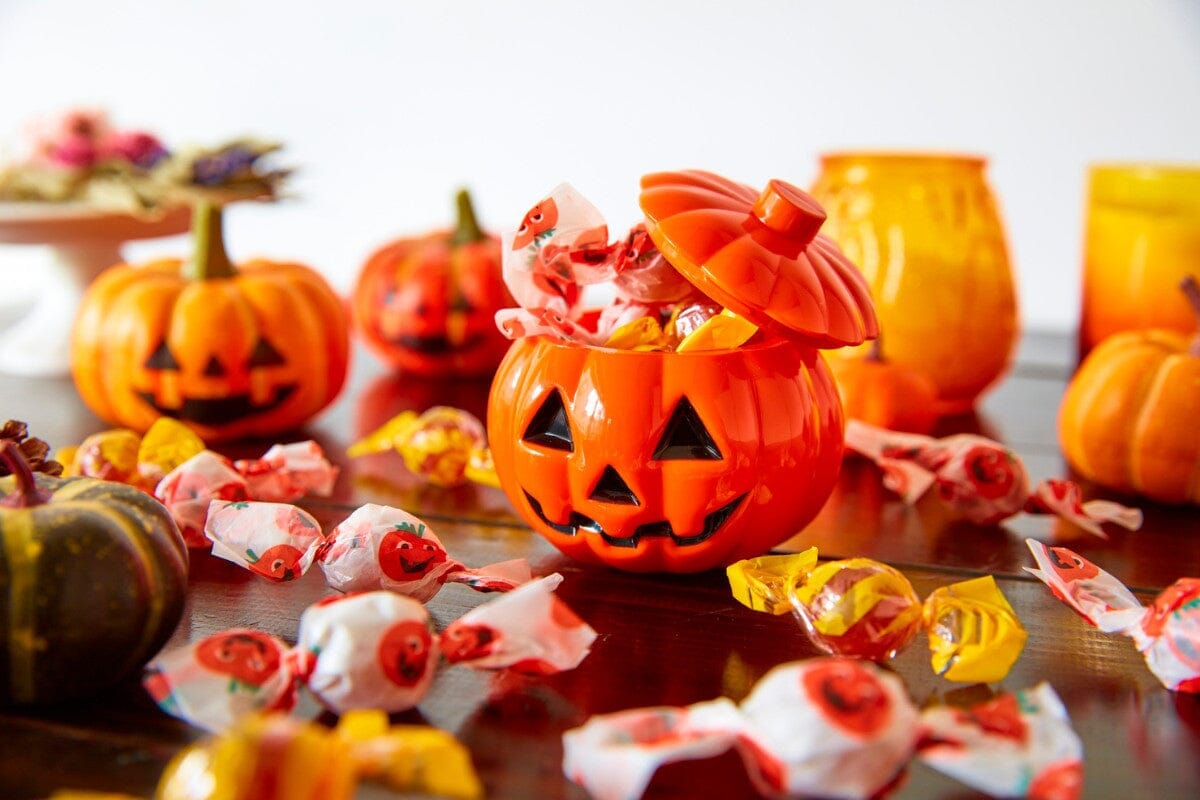 Pumpkin filled with Halloween candy, resting on wooden table.