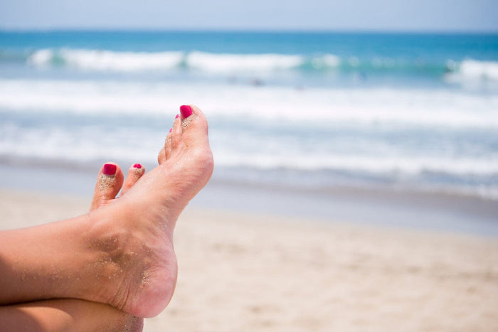 woman's sandy feet on the beach on a sunny day.