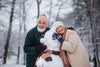 senior couple smiling as they build a snowman outside