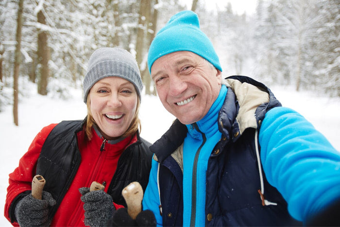 senior couple smiling for a picture while outside in the snow hiking.