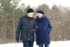 senior couple walking in winter forest, talking and smiling together.