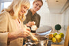 older woman and her daughter making soup in a pot on the stove together