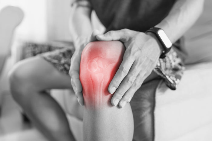 black and white photo of someone holding their red, inflamed knee