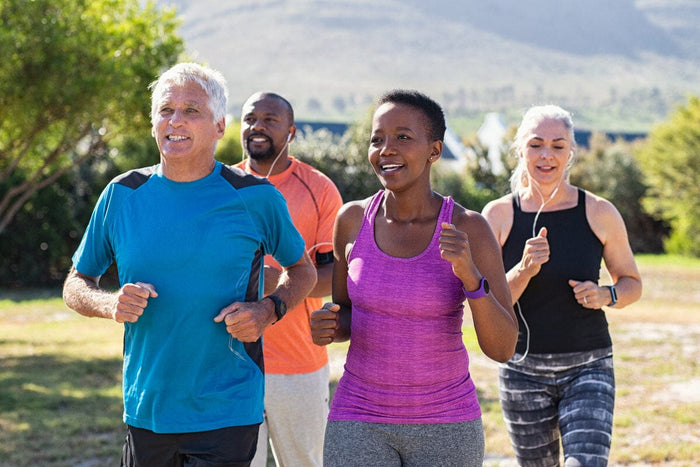 group of 4 older adults jogging outside together