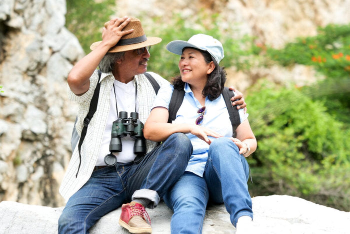 older couple enjoying nature, sitting on a rock